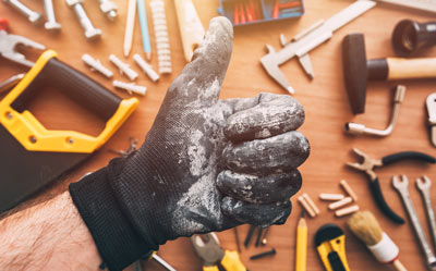 gloved hand giving thumbs up surrounded by various tools representing 7 essential tools for DIY projects