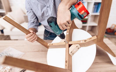 man assembling a wooden chair using a drill in a DIY project for home improvement and interior design 4 tips for assembly