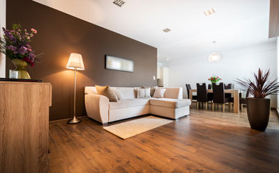 a cozy living room with modern furniture including a sectional sofa a floor lamp and a wooden dining table surrounded by six chairs with decorative plants and a soft rug