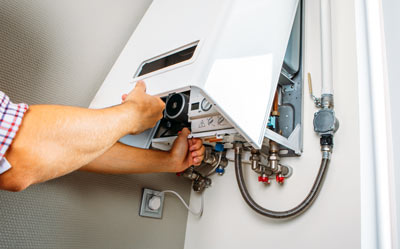 a person performing maintenance on a white boiler unit showing five key components in focus