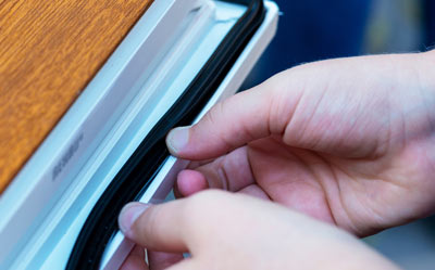 hands installing a seal on a door with wooden surface applies to sealing gaps for better insulation