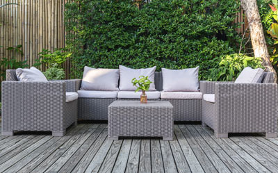 outdoor seating arrangement with three plush gray cushions on a wooden deck surrounded by greenery 3 piece furniture set