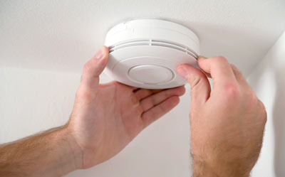 hands installing smoke detector on ceiling with focus on safety and prevention